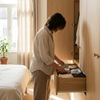 Persoon kiest luchtig, ademend ondergoed in een lichte slaapkamer, met frisse ochtendzon en nette basics die comfort bij warm weer uitstralen.