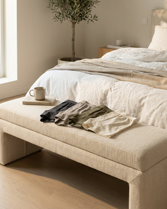 Neatly folded Sloggi basics in soft neutral tones on a bright bedroom bench, suggesting a practical 3+1 underwear offer for everyday comfort.